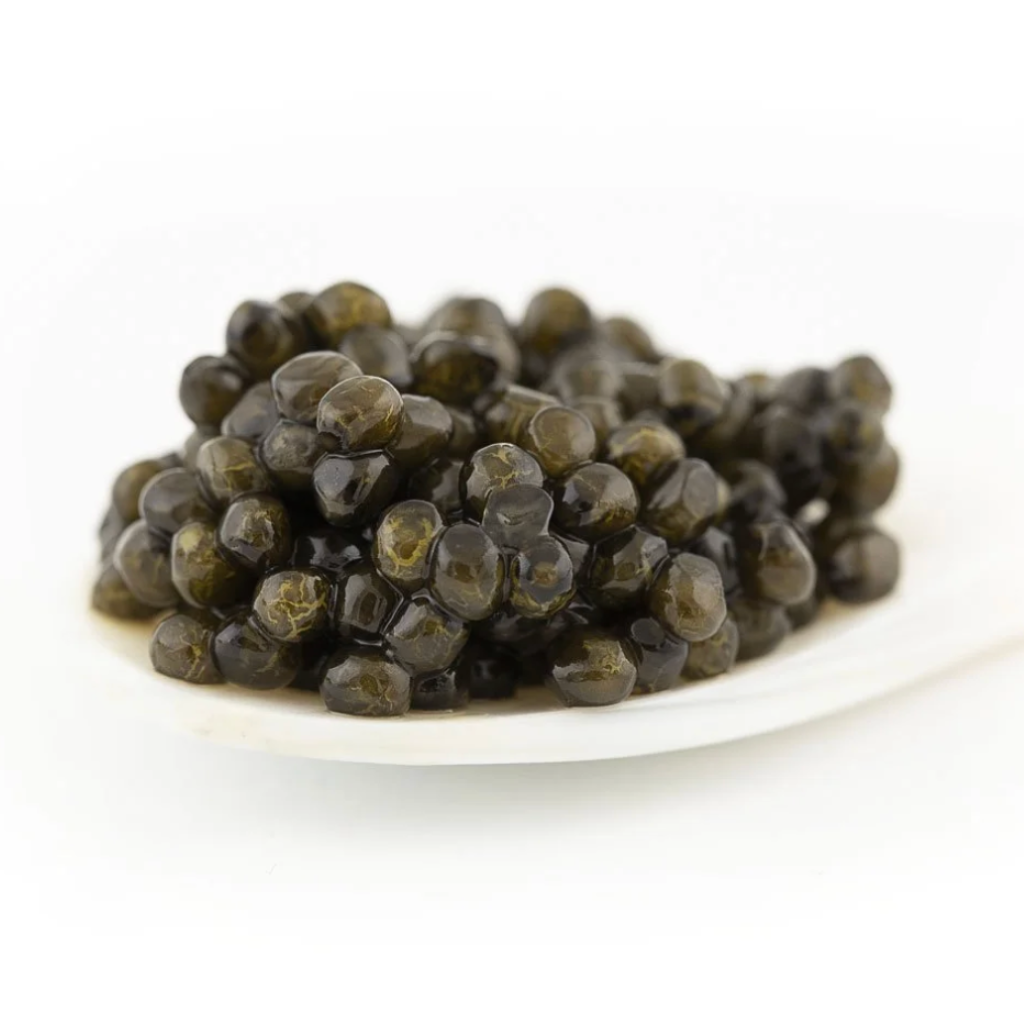 Close-up macro shot of glossy, dark Caviar d'Eden Oscietra pearls delicately served on a traditional white mother-of-pearl spoon